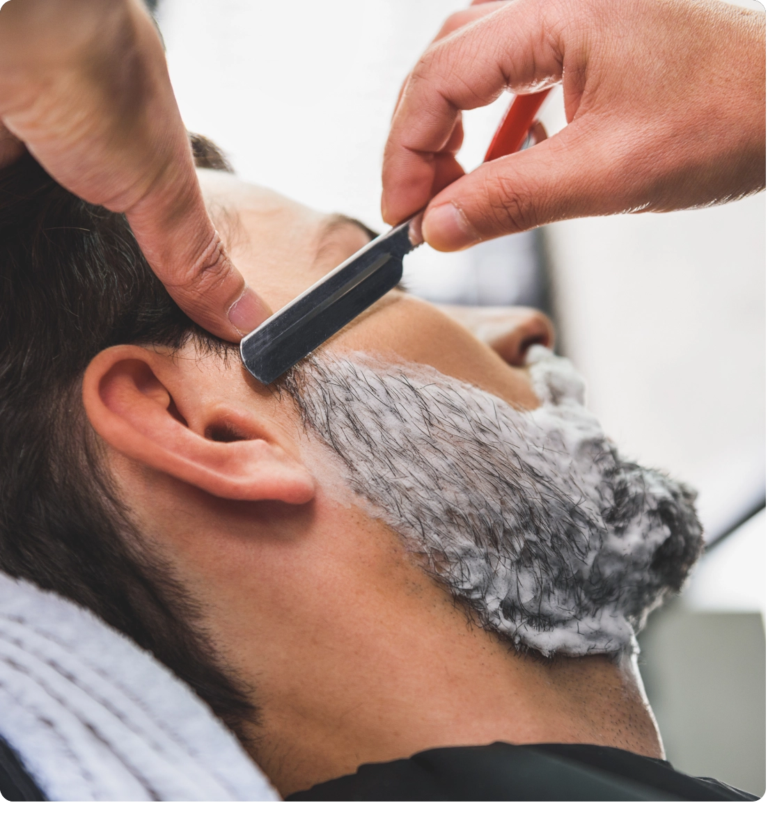 A man getting his beard shaved by another person.